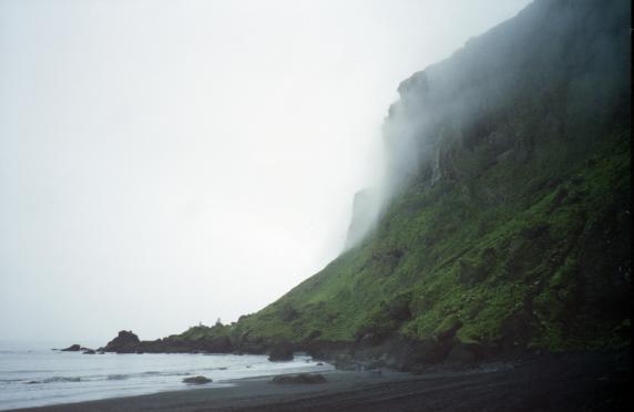 The black sands of the beach at Vk with mist hanging over the cliffs